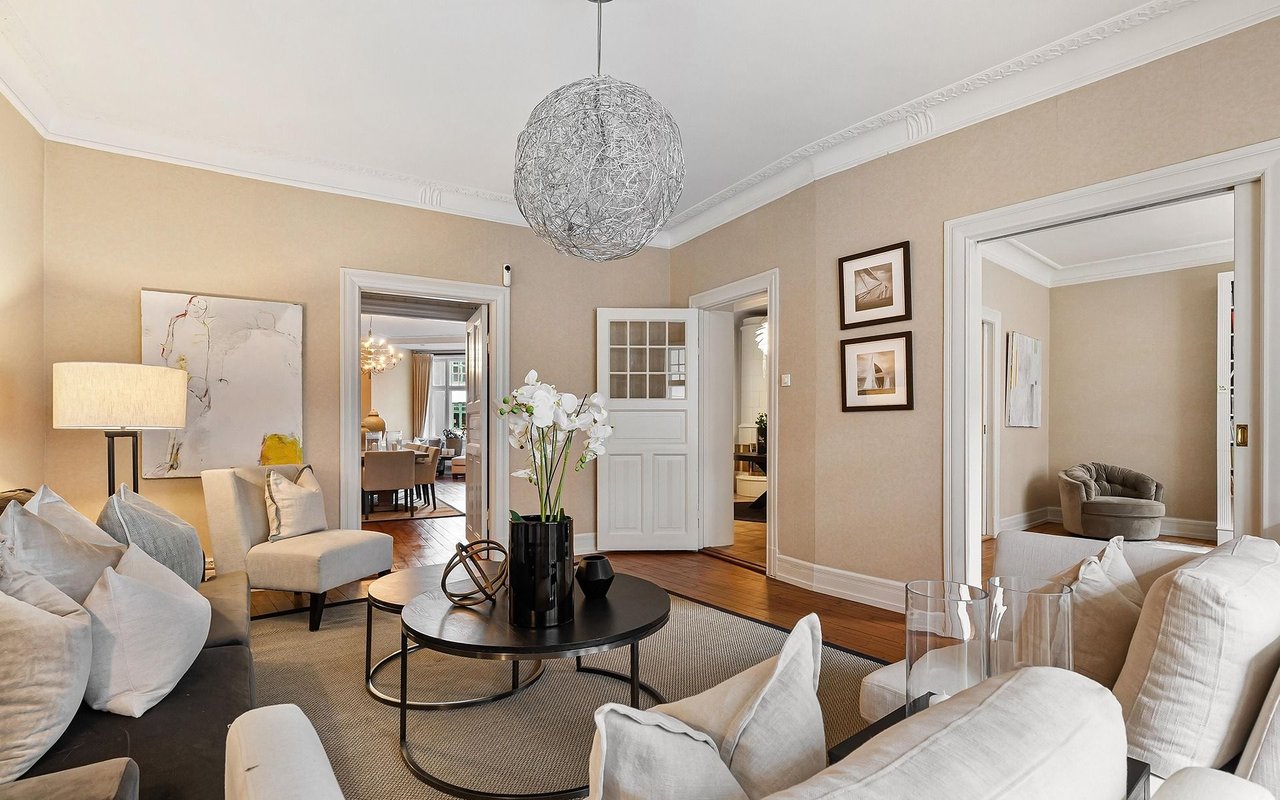 Furnished living room with white seating, a black coffee table, and a spherical pendant light.