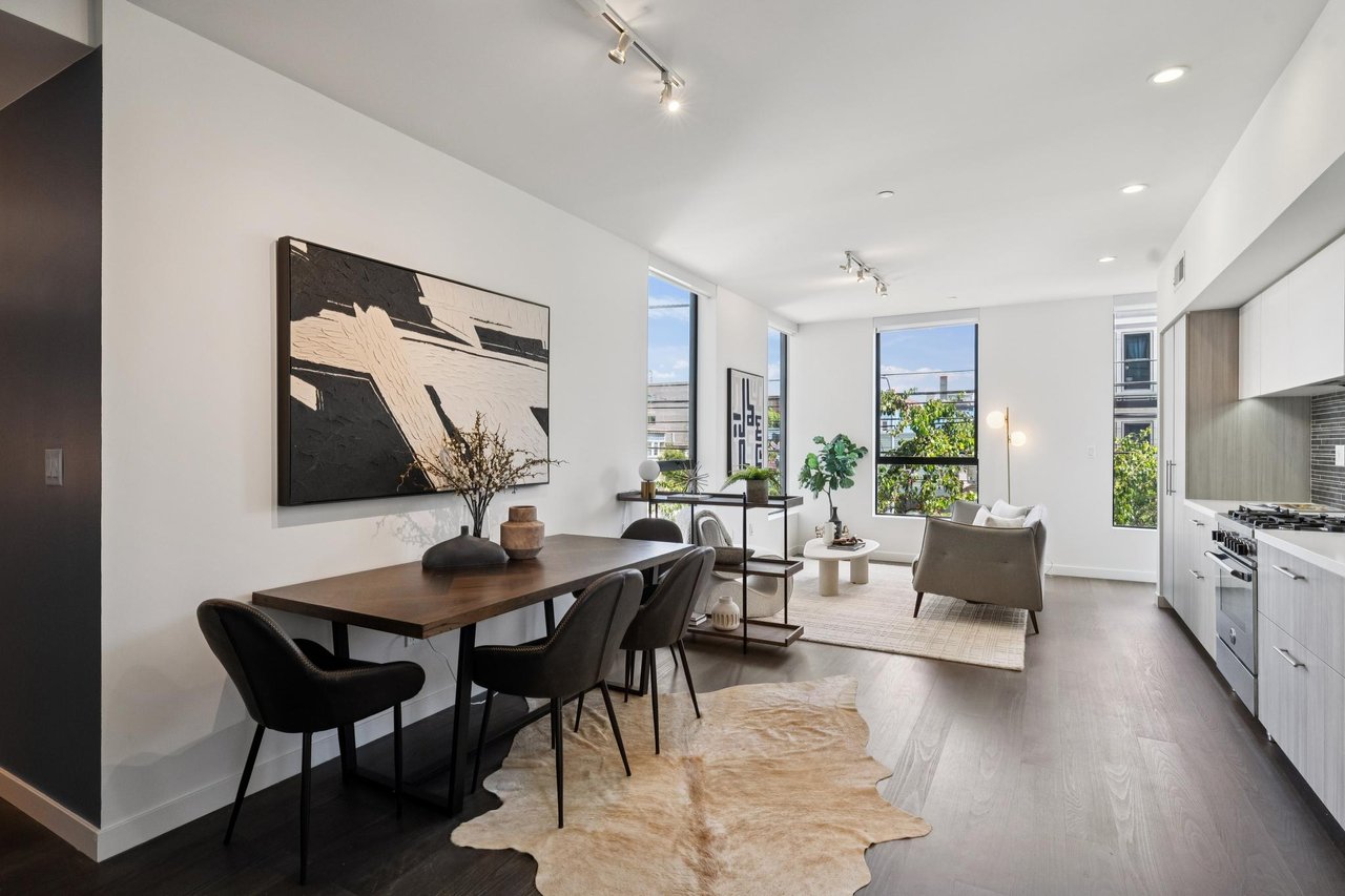 Open-plan condo interior with a dining area, modern kitchen, and large windows.
