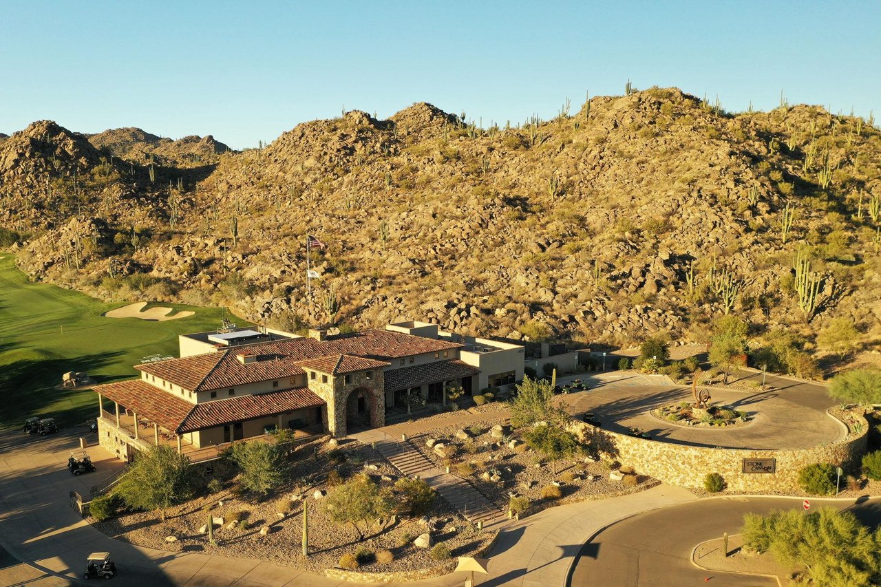 Stone Canyon clubhouse beside a golf course, with a rocky cactus-covered hillside behind it.