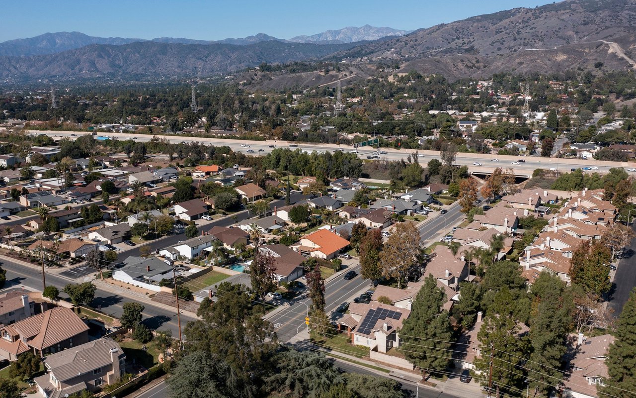 Aerial view of San Dimas neighborhoods, highway, and surrounding mountains.