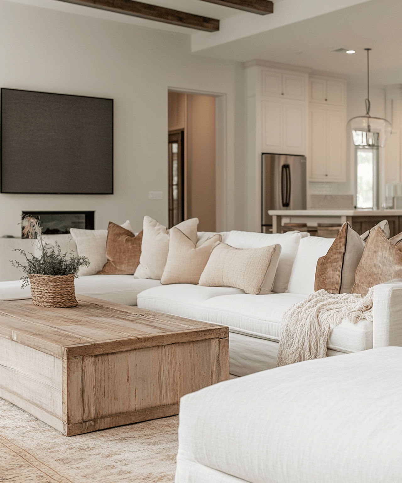 Living room with a white sectional, rustic wood coffee table, fireplace, and open kitchen.