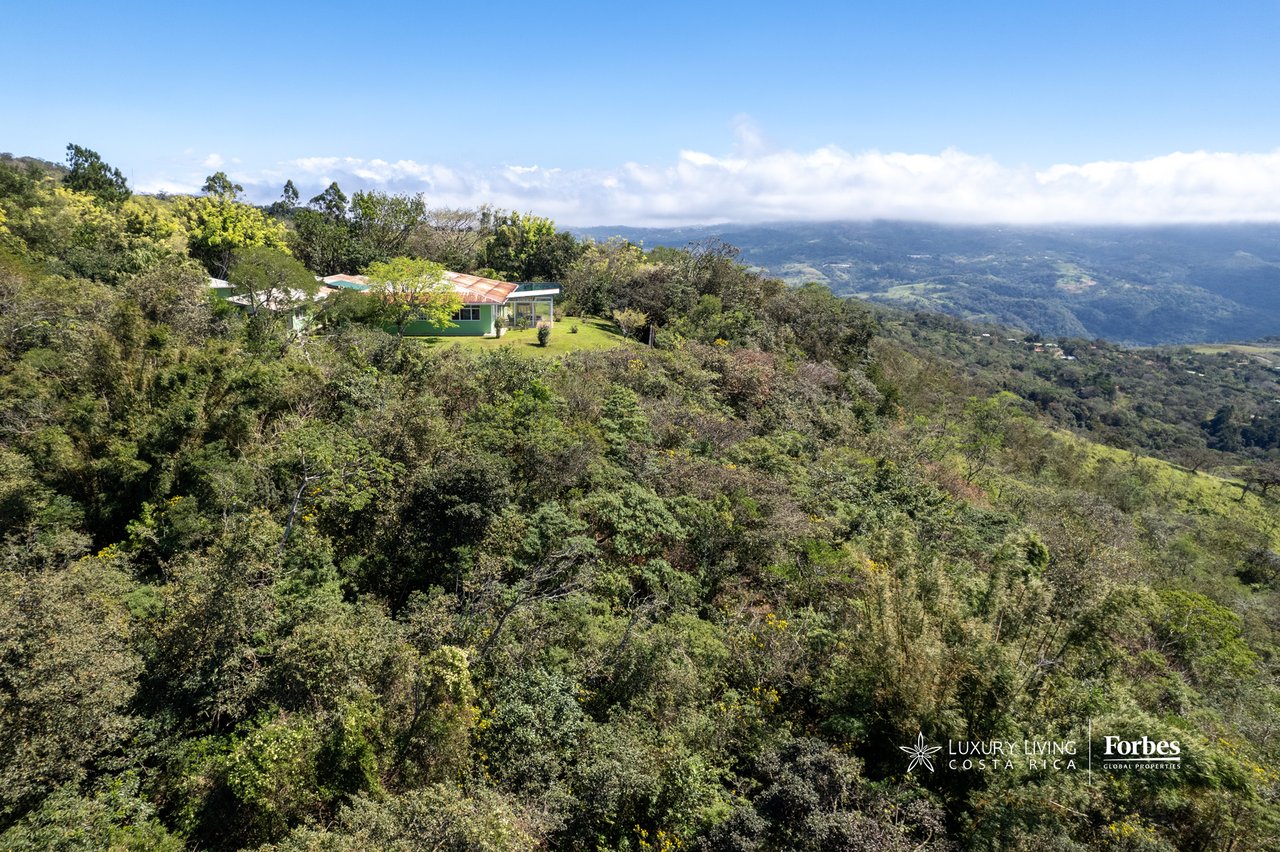 Mountain retreat surrounded by forest, overlooking a broad valley and distant ridgelines.