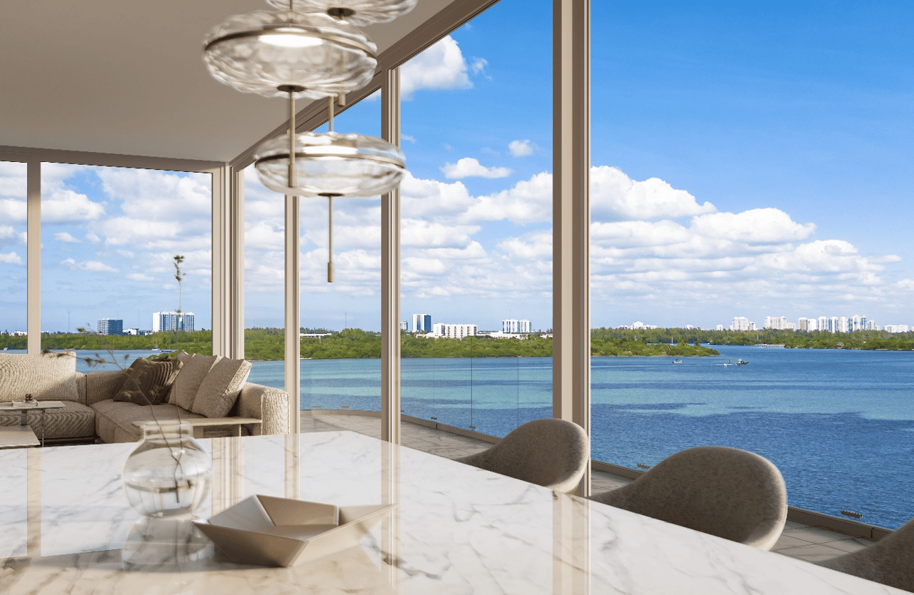 Staged condo living and dining area with floor-to-ceiling windows overlooking the bay.
