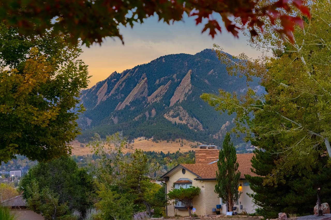 Flatirons at sunset framed by autumn trees above homes in Boulder's Hillcrest neighborhood near 2003 Balsam Drive