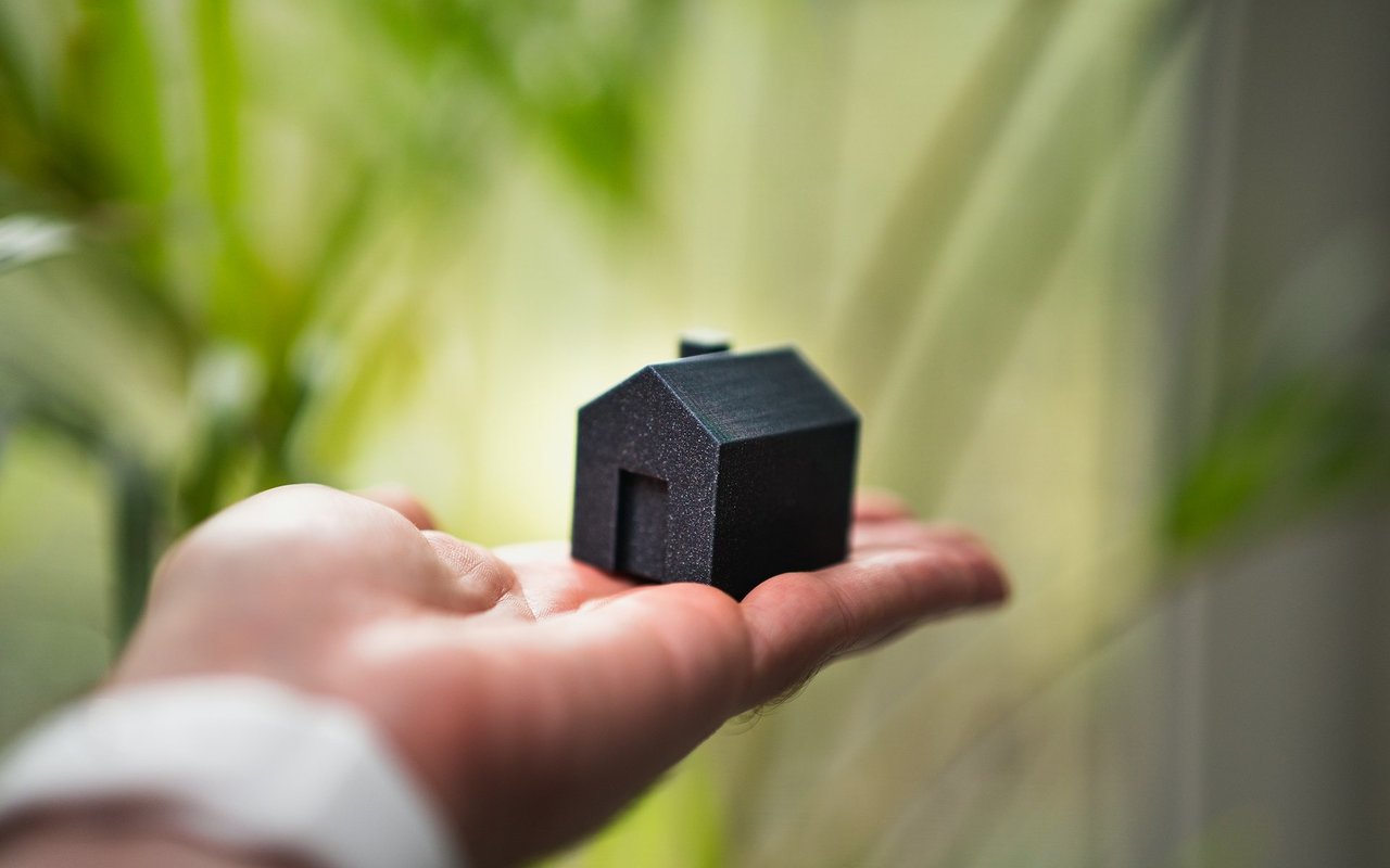 Small black house model resting in an open hand