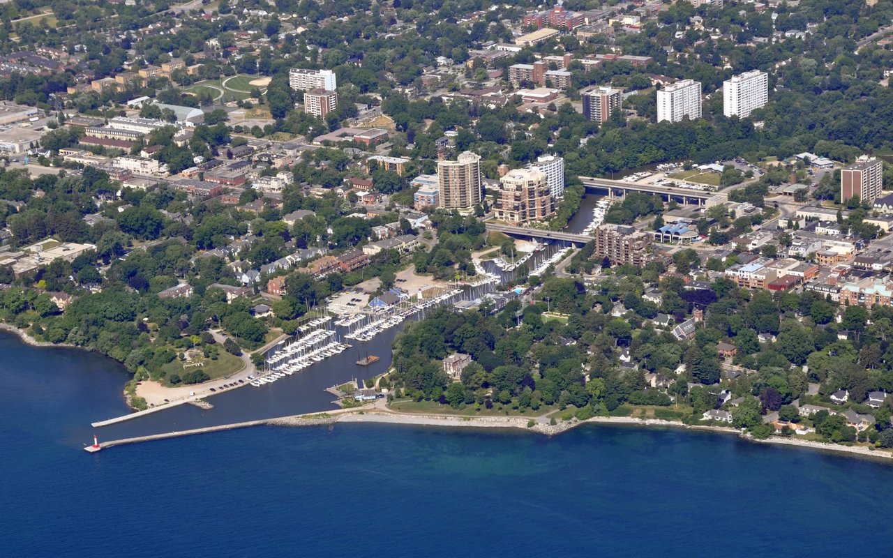 An aerial view of Oakville, Ontario, showing a waterfront community with a marina, residential buildings, and green spaces