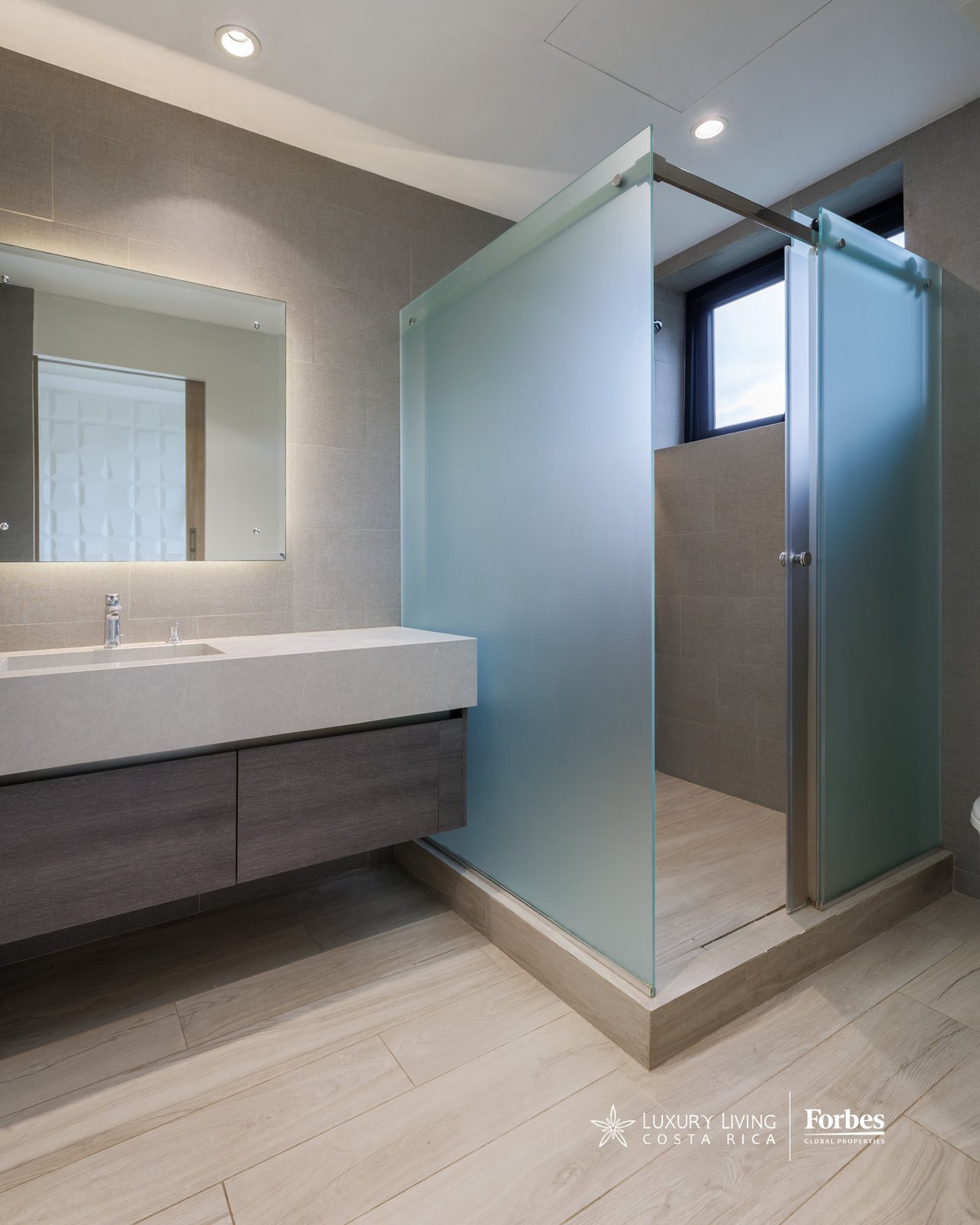 Modern bathroom with a floating vanity and a frosted-glass walk-in shower.