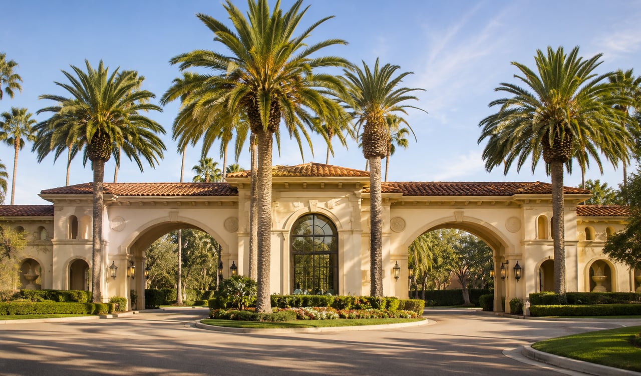 Mediterranean-style gated entrance to an upscale residential community in Tarzana, California, surrounded by palm trees and lush landscaping.