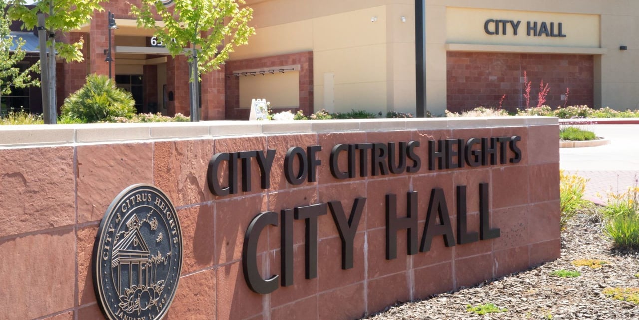 A close-up of a city hall sign mounted on a brick wall.