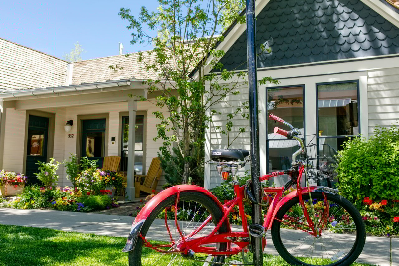 Historic Victorian home on tree-lined street in Aspen's West End neighborhood with mountain views and mature landscaping, showcasing the area's characteristic charm and architectural heritage.