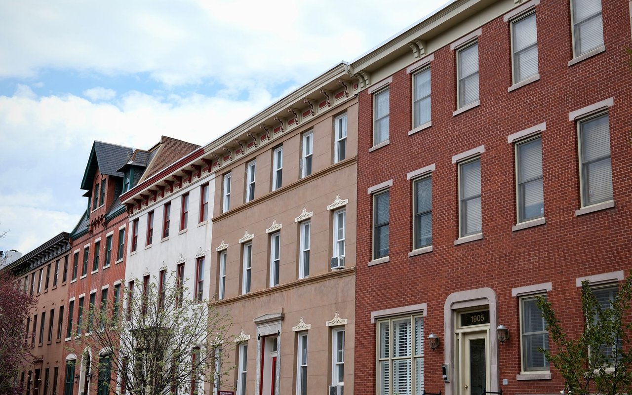 Attached brick and stone rowhouses with tall windows and ornate cornices; nearest doorway marked 1905.