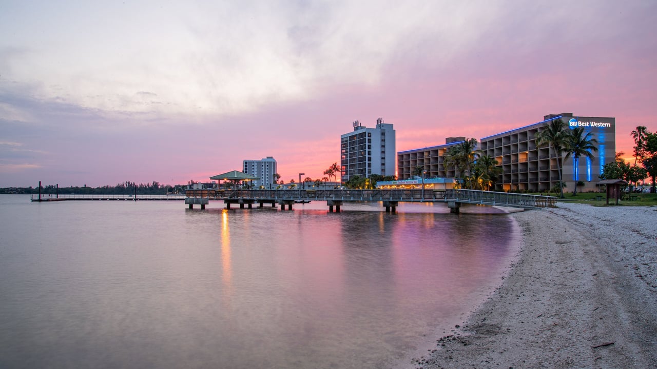 Waterfront beach and pier beside a Best Western hotel at dusk.
