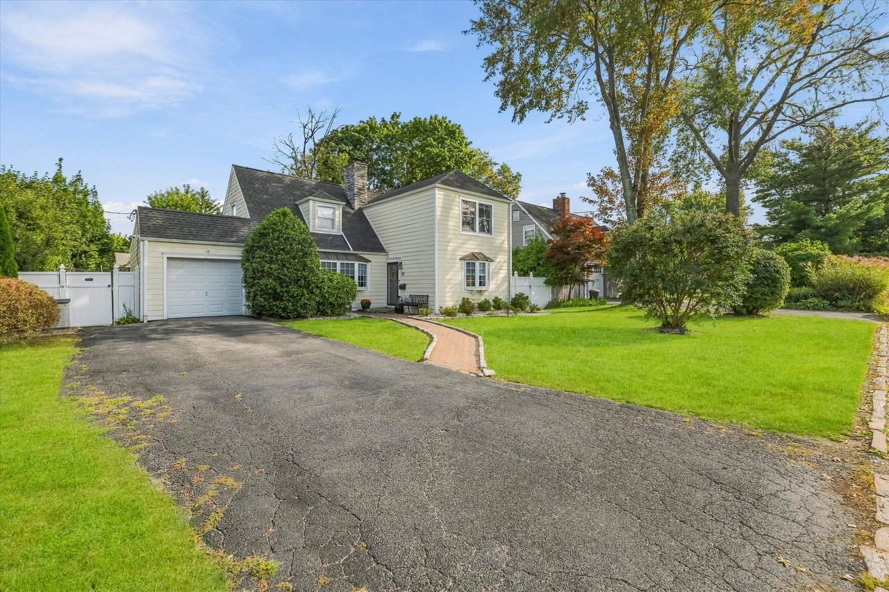 Two-story home with an attached garage, broad driveway, brick walkway, and landscaped lawn.