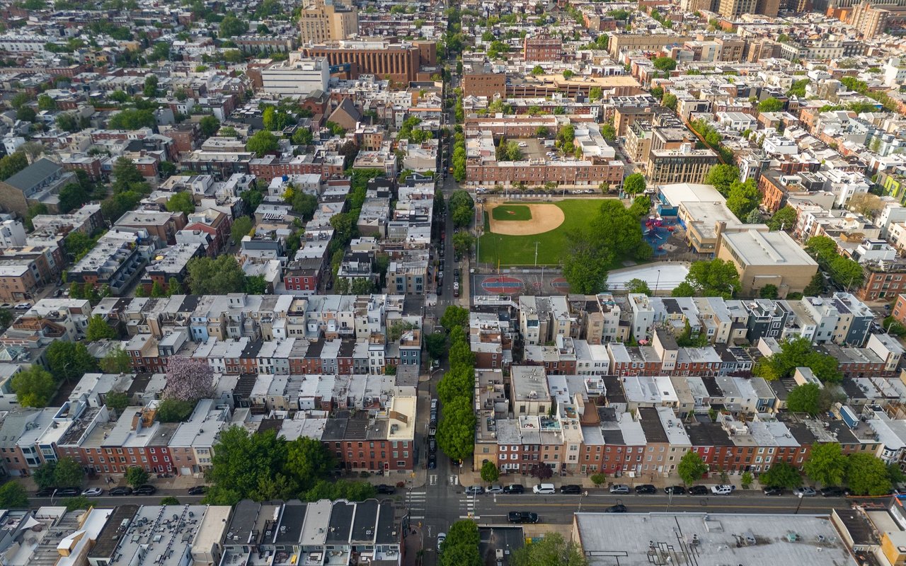 Aerial view of South Philadelphia rowhomes surrounding a neighborhood baseball field and recreation courts.