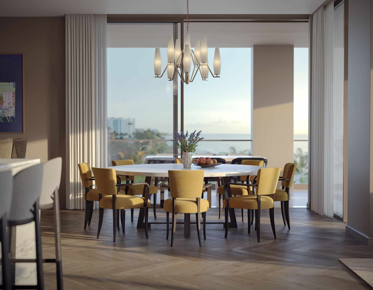Dining room with a round table and chandelier overlooking the water through expansive windows.