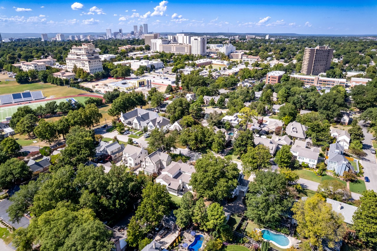 Aerial view of Tulsa’s tree-lined neighborhoods, sports field, and downtown skyline.
