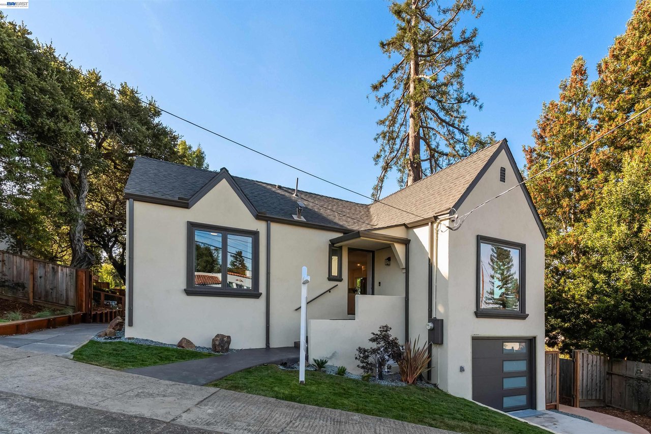 Oakland home with light stucco walls, dark trim, gabled roof, and a sloping driveway.