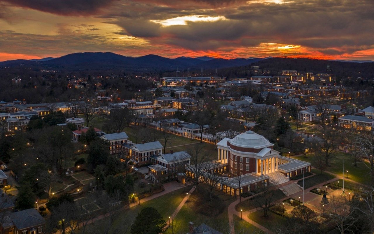Aerial view of the University of Virginia Rotunda and campus at dusk, with the Blue Ridge Mountains beyond.