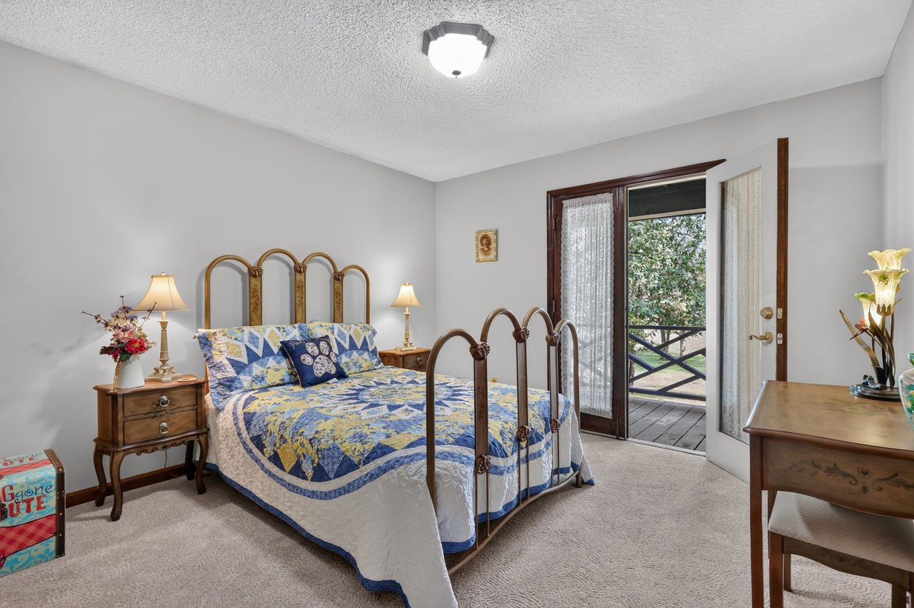 Bedroom with a patchwork quilt and open balcony door.