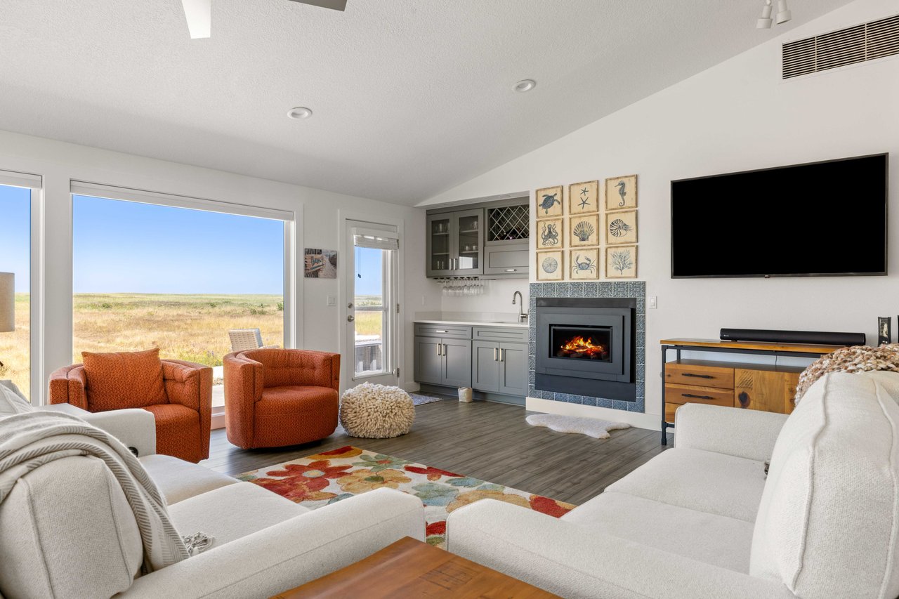 Light-filled coastal living room with ocean views, vaulted ceilings, modern fireplace, built-in wet bar, and large windows showcasing the natural beauty of the Oregon Coast
