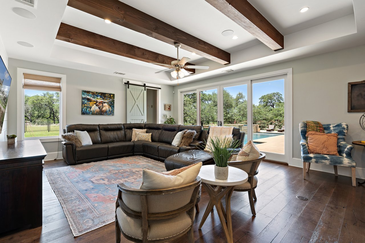 Family room at 335 Winning Colors with a leather sectional and beamed ceiling, opening toward the pool.