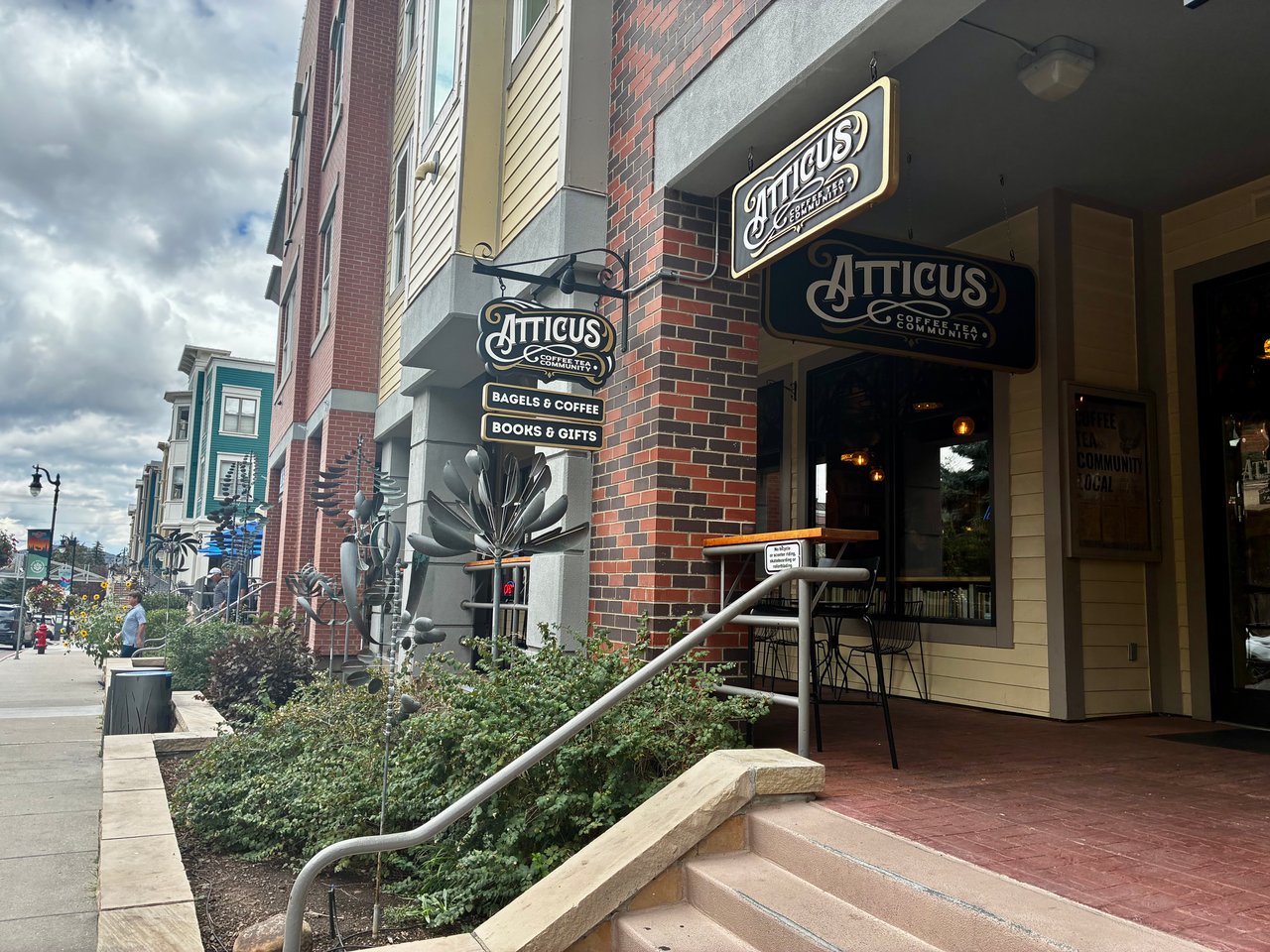 Atticus Coffee, Tea & Community storefront with hanging signs and outdoor seating.
