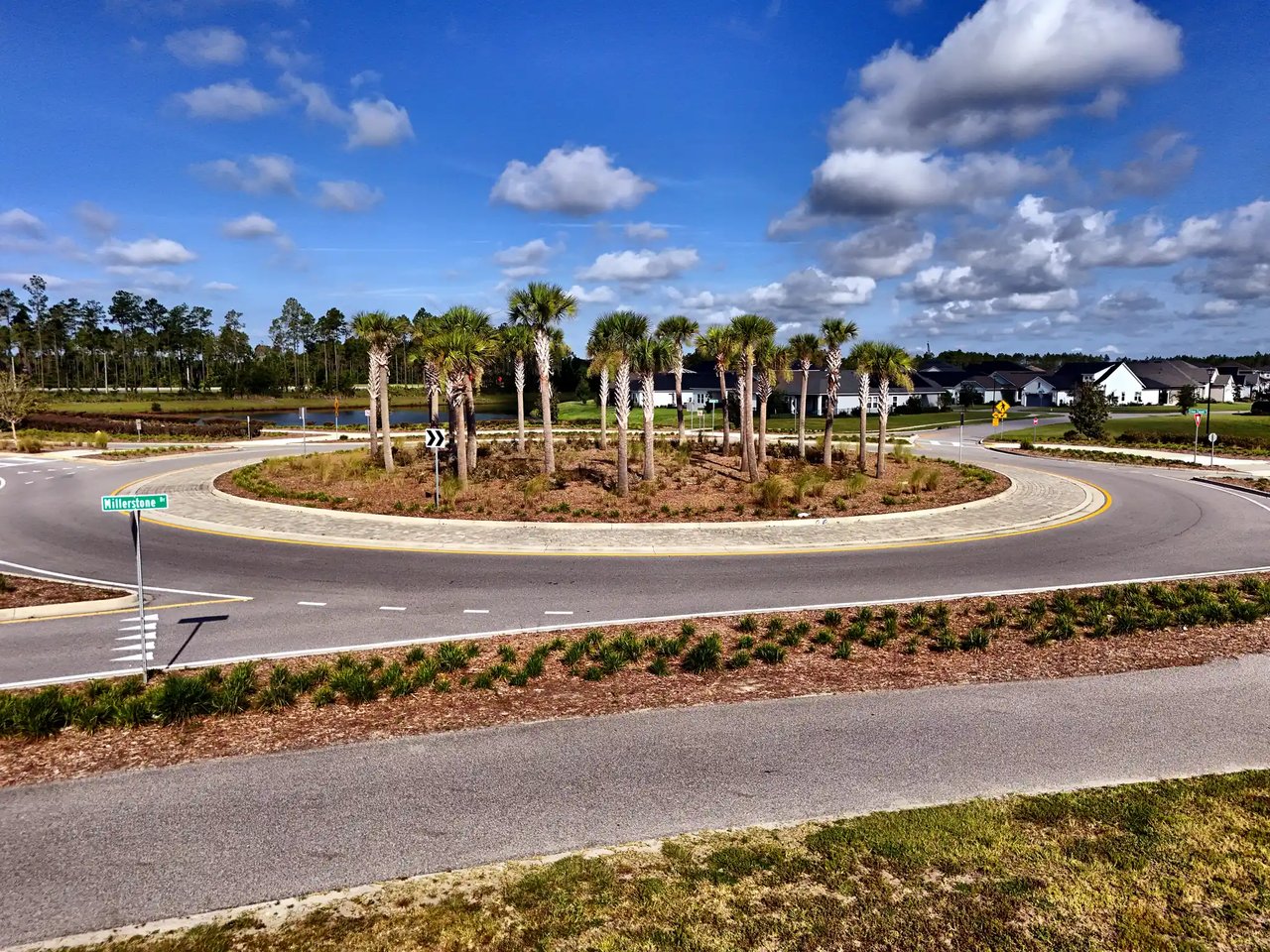 Palm-lined neighborhood roundabout with new homes and a Millstone Ct street sign.