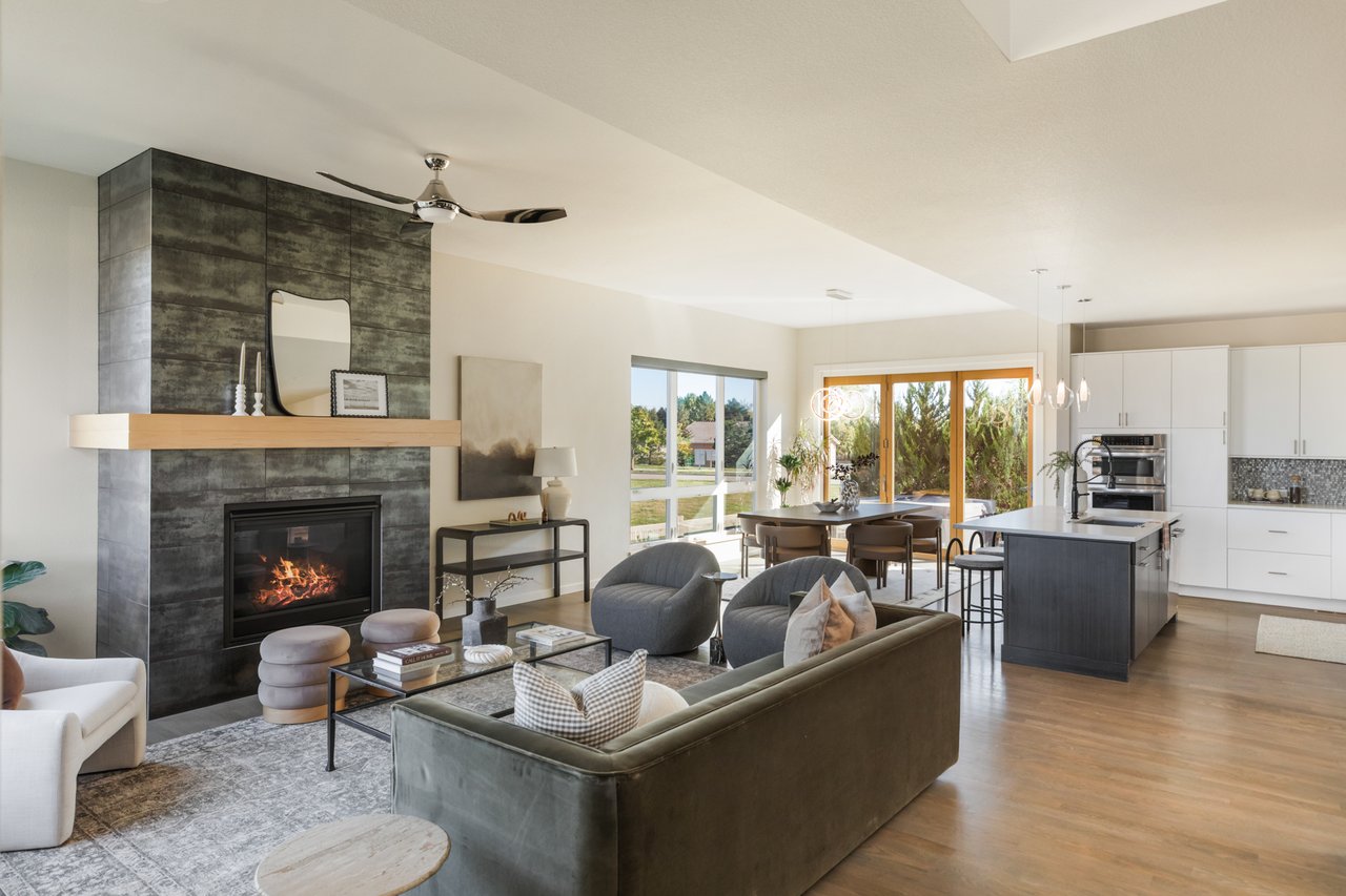 Living room with a dark tile fireplace, sectional, and ceiling fan, open to the kitchen and dining area