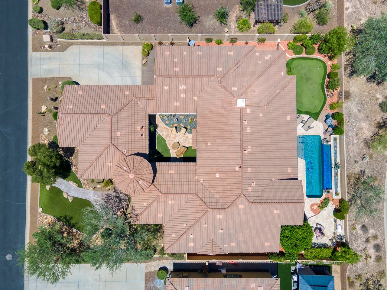 Top-down aerial view of a large suburban home with a pool, patio, and landscaped yard beside a body of water.