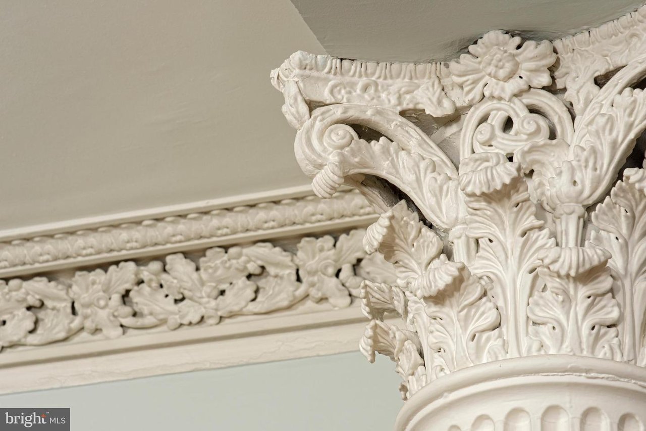 Ornate carved white column capital and decorative ceiling molding.
