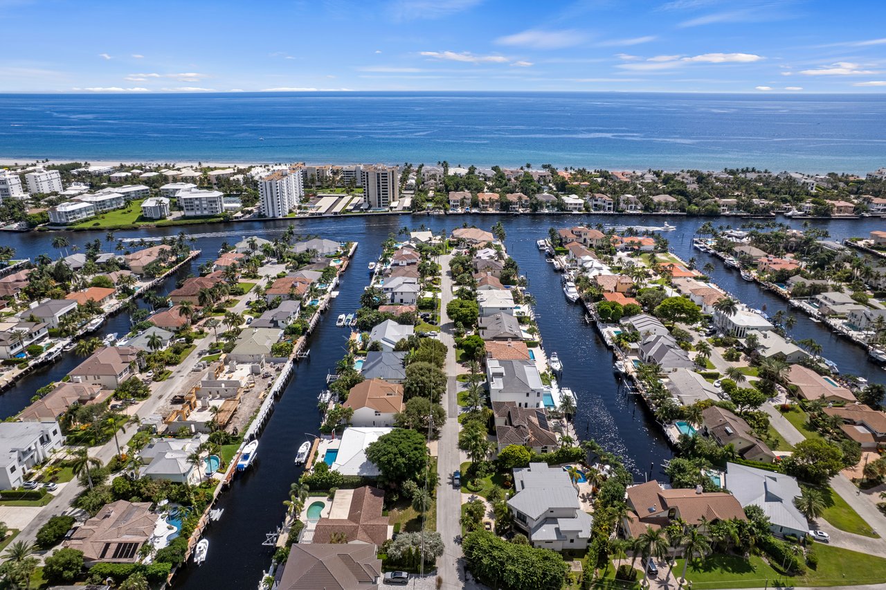 Aerial view of canal-front homes and boats, with the Atlantic Ocean beyond.