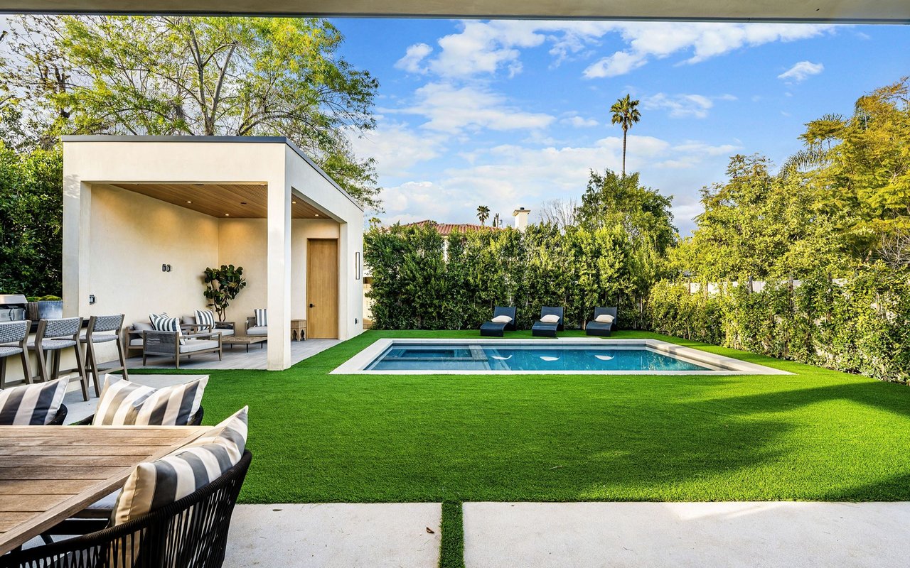 Modern backyard with a rectangular pool, covered patio, and outdoor lounge seating.