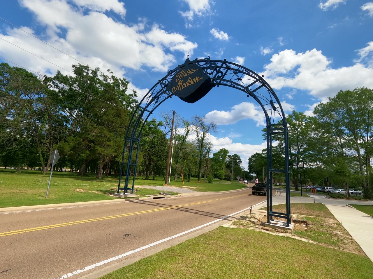 Historic Madison entrance arch spanning a tree-lined road.