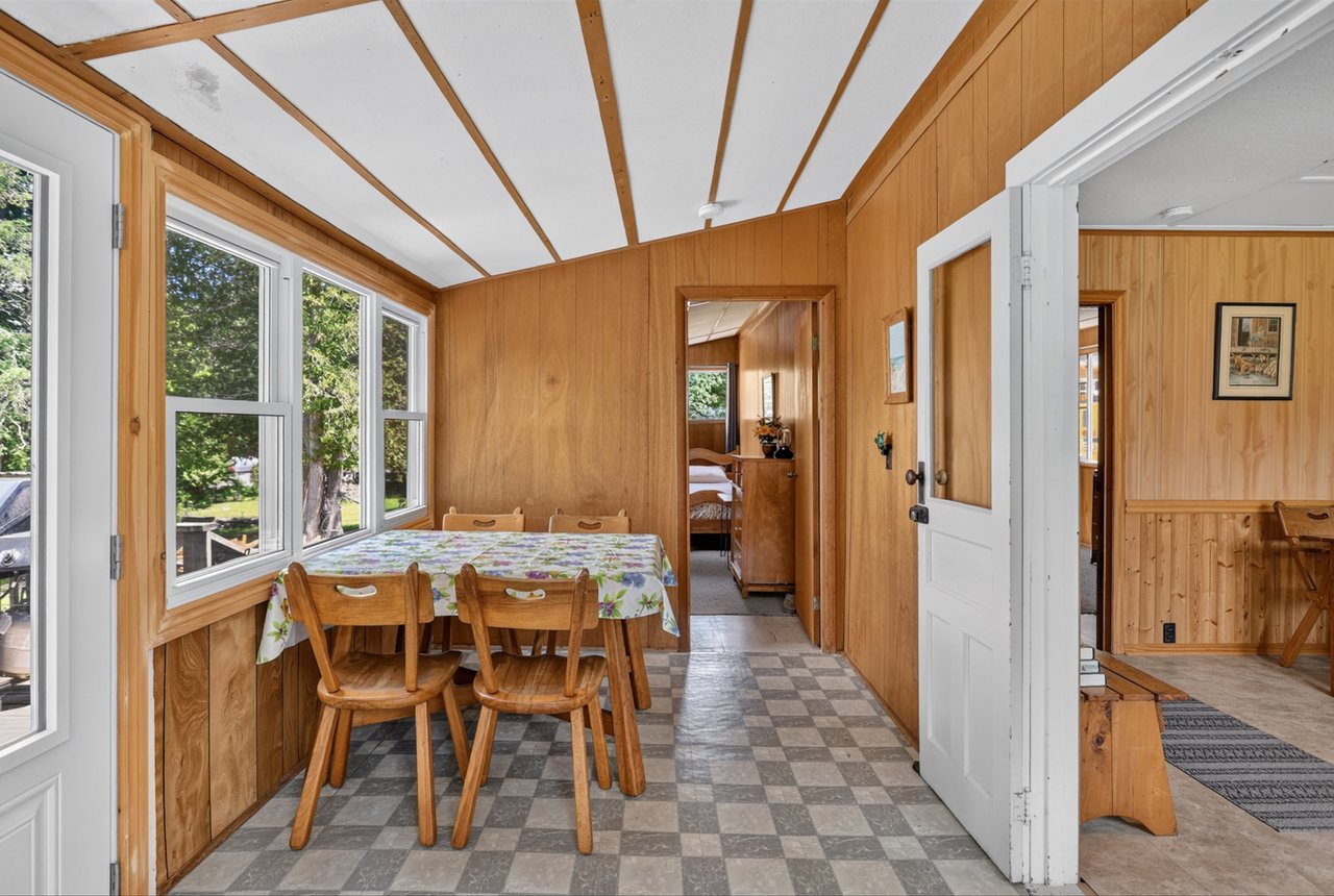 Dining area with wood-paneled walls, a checkered floor, and a table beside large windows.
