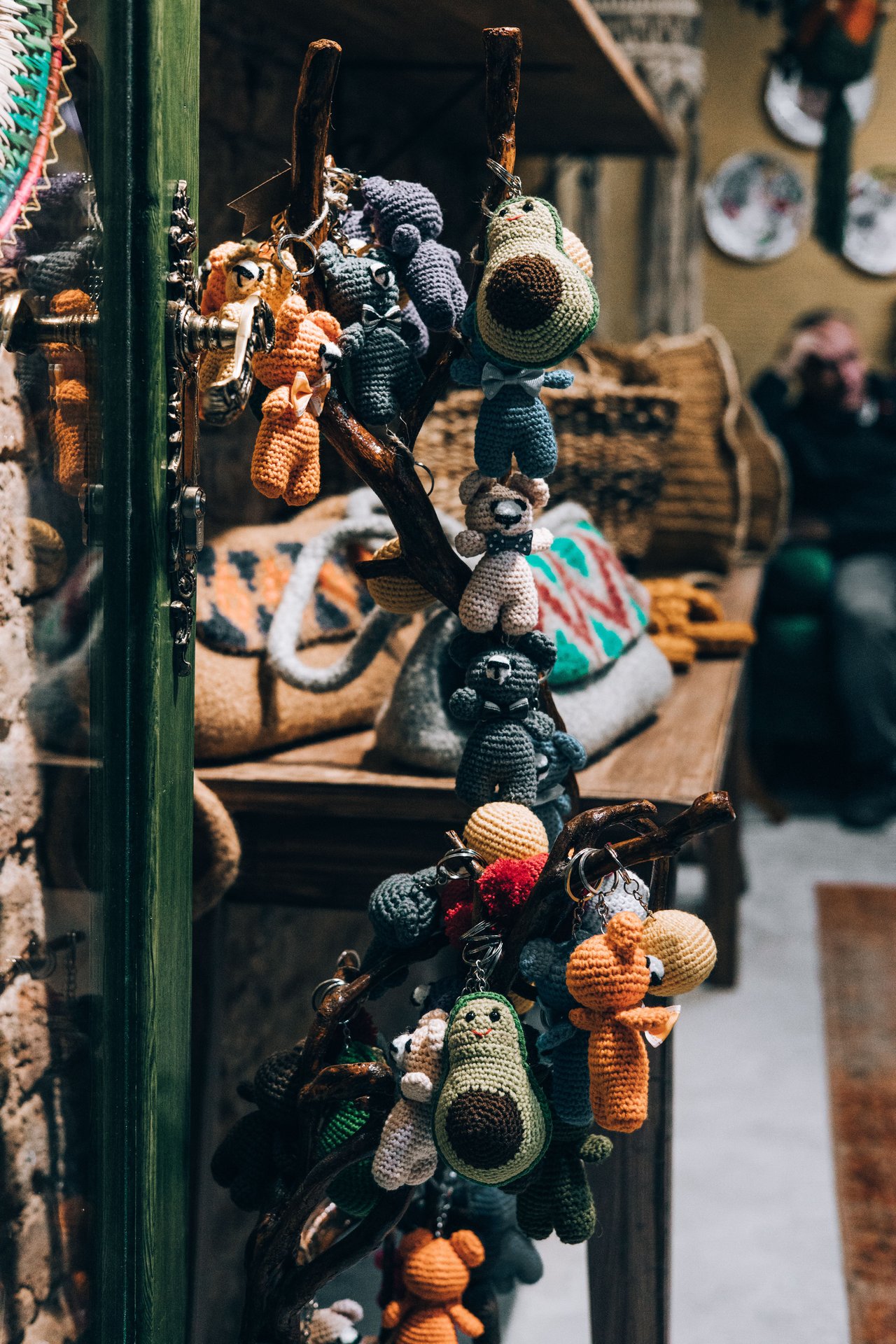 Crocheted animal toys and keychains hang from a display stand in a shop.