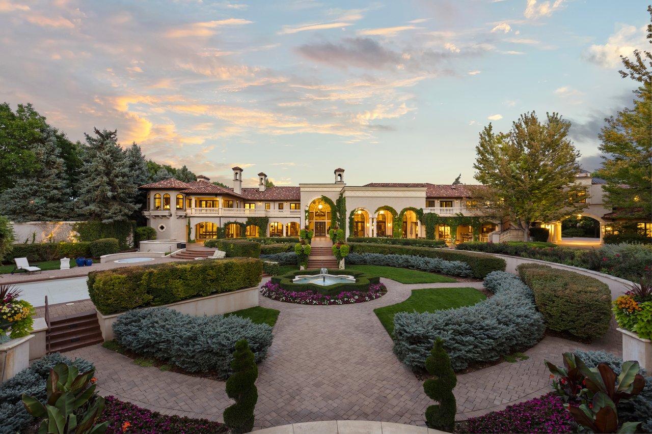 Estate residence framed by formal gardens, curved brick paths, clipped hedges, and a central fountain.