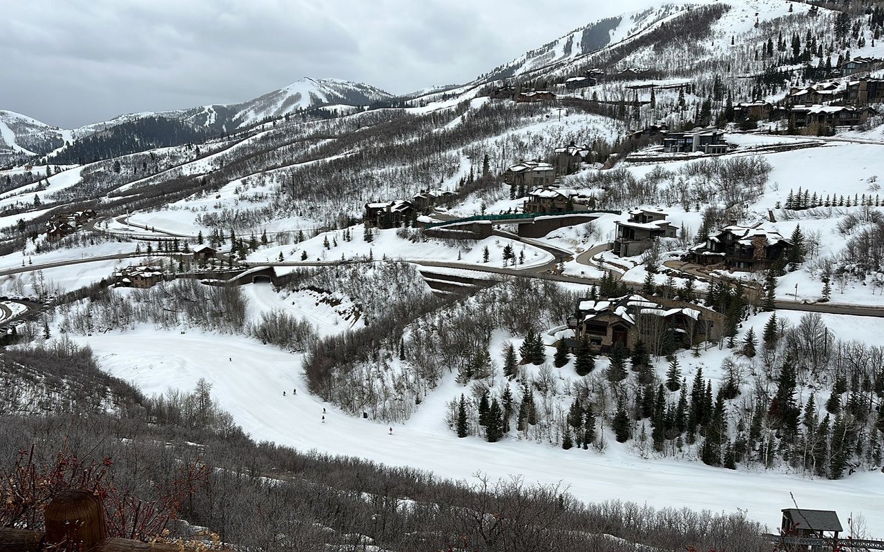Snow-covered Deer Crest homes overlook a ski run winding through a wooded mountain neighborhood.