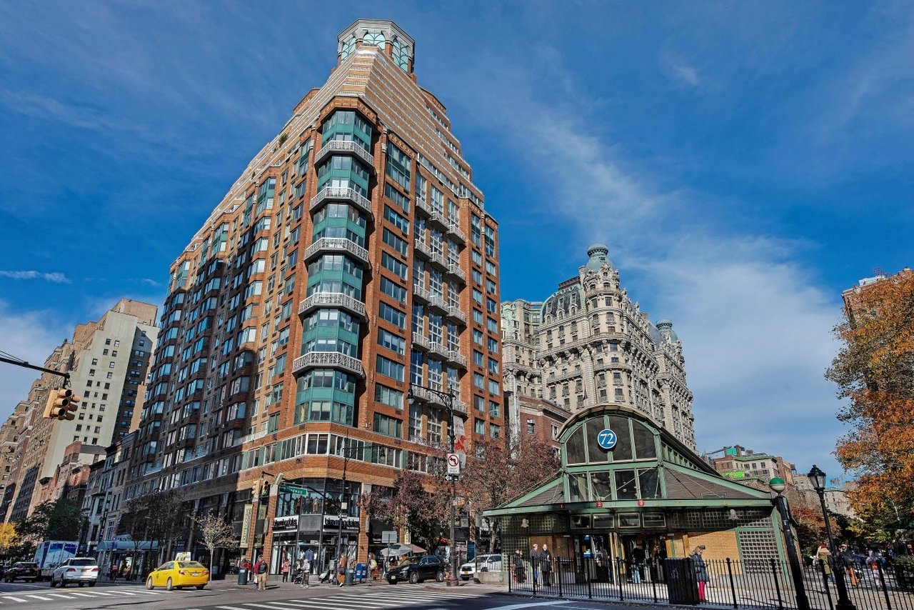 Red-brick residential tower with curved corner windows beside the 72nd Street subway entrance.