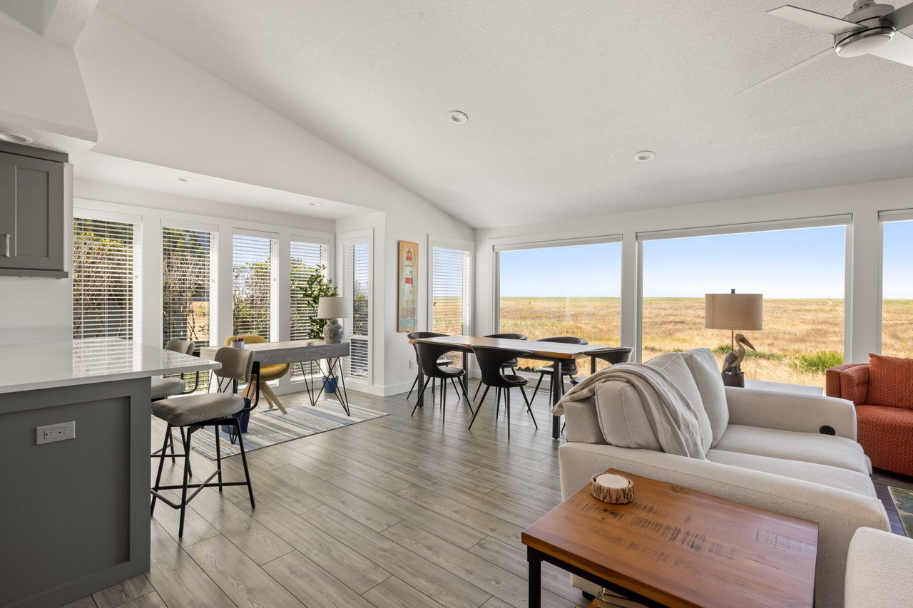 Bright open-concept living and dining space featuring floor-to-ceiling windows, vaulted ceilings, modern finishes, and sweeping Oregon Coast views.