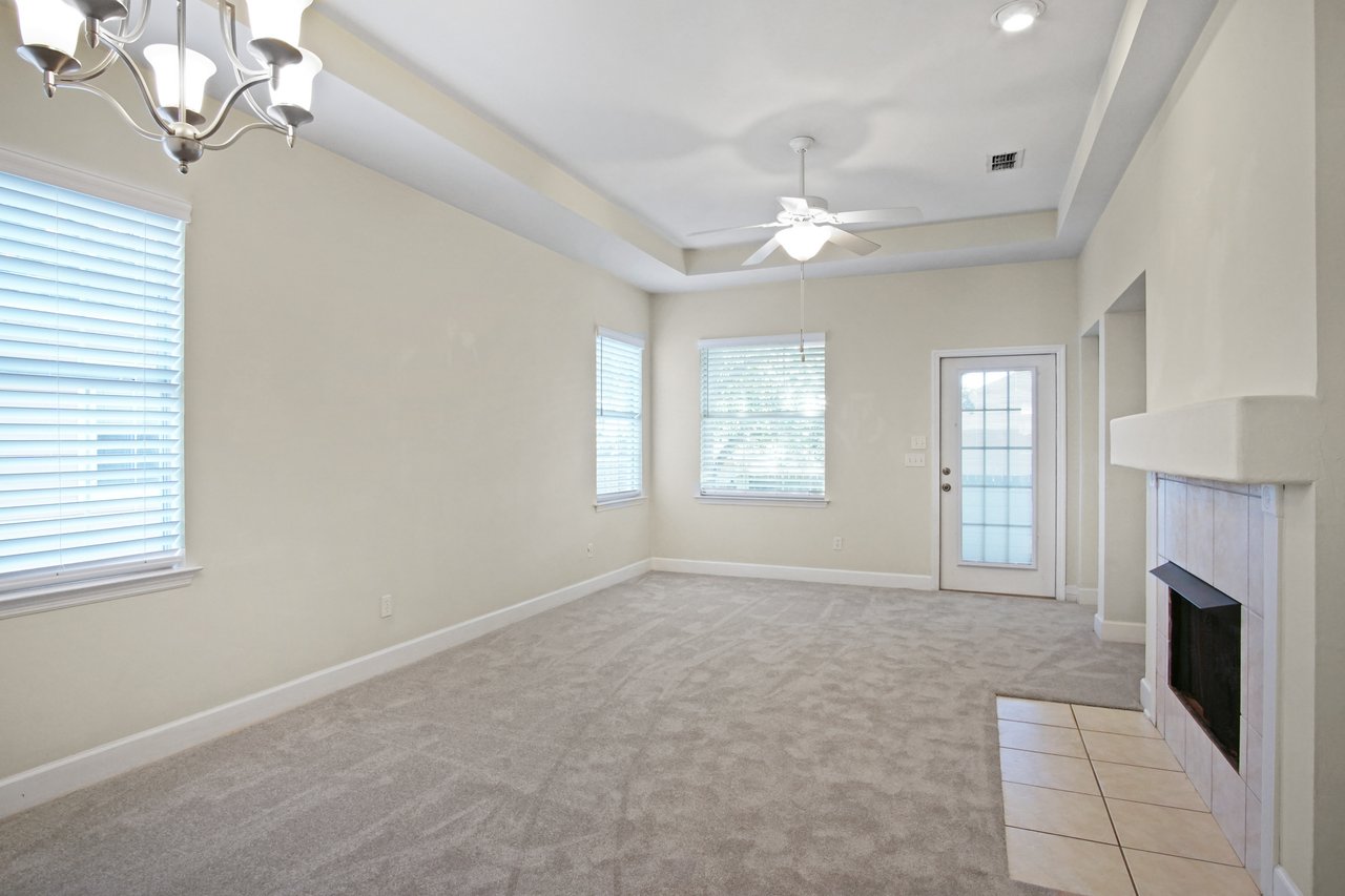 Living room at 5441 Hampton Hill Circle, Tallahassee, Florida 32311 featuring fireplace, tray ceiling, ceiling fan, and door to screened porch.