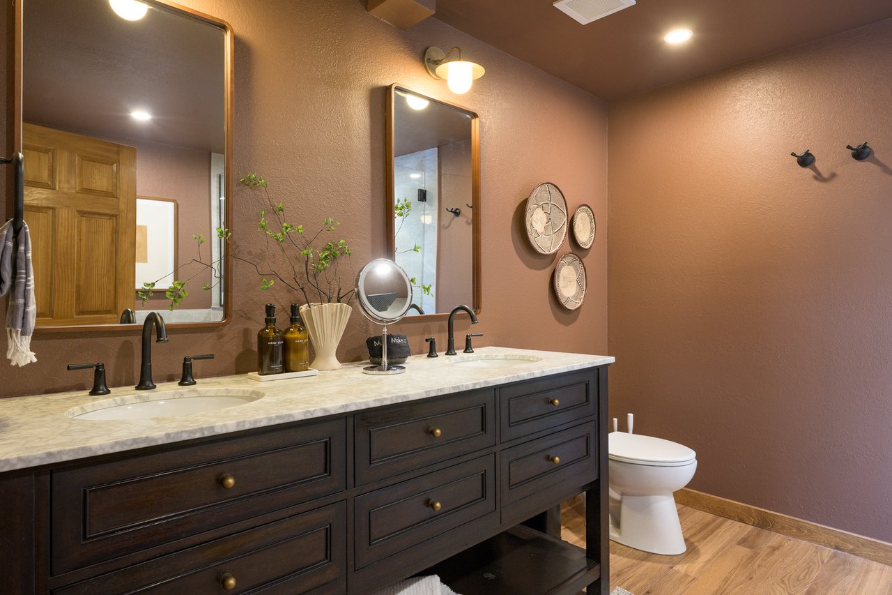 Bathroom with a dark double vanity, marble countertop, two sinks, and framed mirrors.