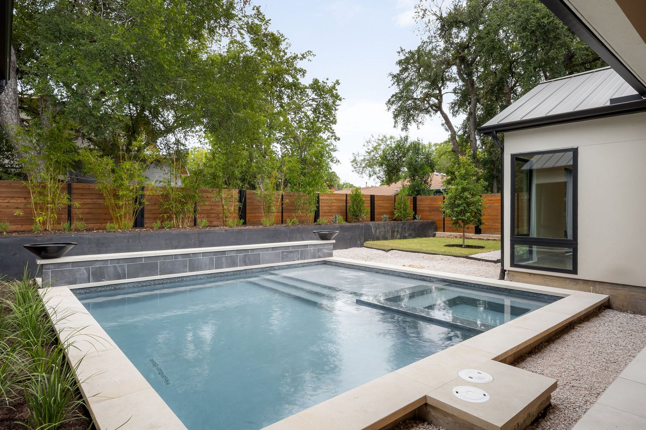 Pool and raised spa at 1001 Bluebonnet Ln (Zilker, Austin), finished with natural stone coping and a privacy fence.