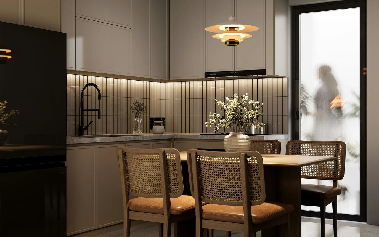 Modern kitchen and dining area with taupe cabinets, cane-back chairs, and a tall frosted-glass door.