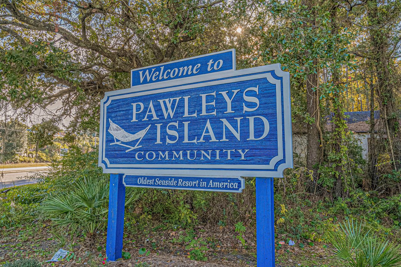 Pawleys Island Community entrance sign beneath mature trees.