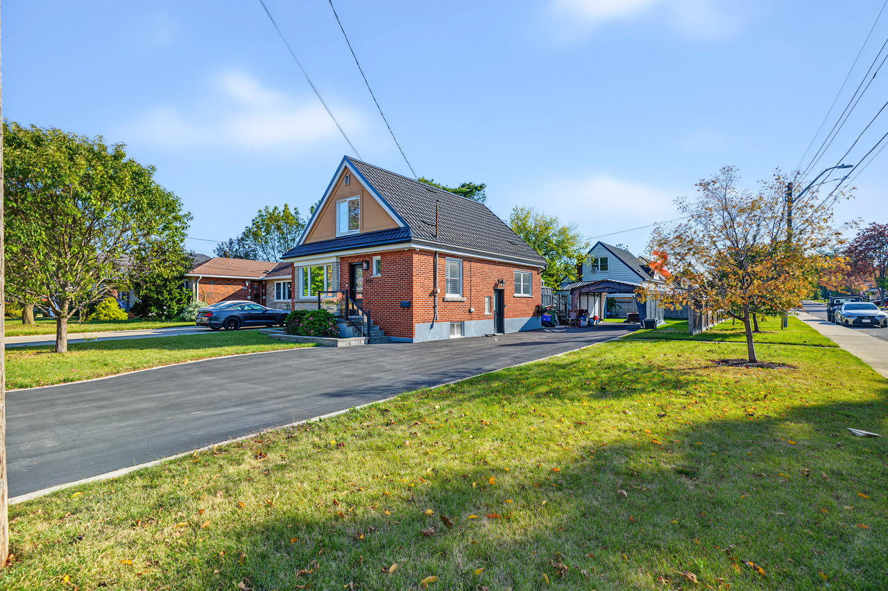 Red-brick house with a steep gabled roof, broad driveway, and front lawn.