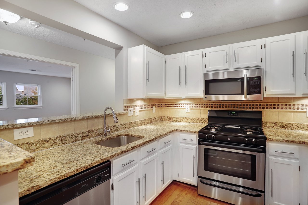Kitchen with white cabinets, granite countertops, stainless steel appliances, and a gas range.