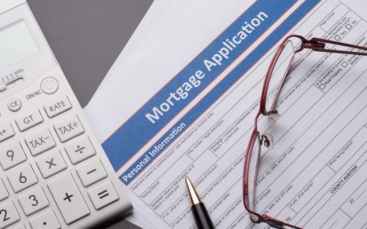 Mortgage application form beside a calculator, red-framed glasses, and a pen.