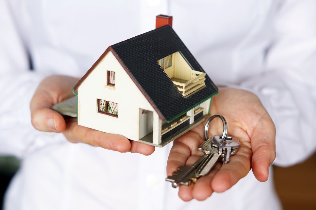 Person holding house model with keys, Cover photo designed by www.Freepik.com
