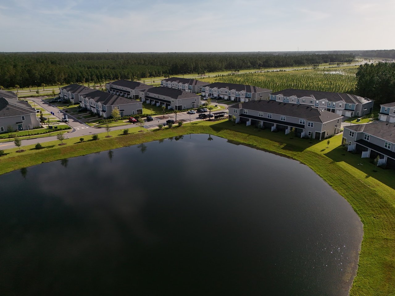 Aerial view of homes surrounding a large pond in a residential neighborhood.