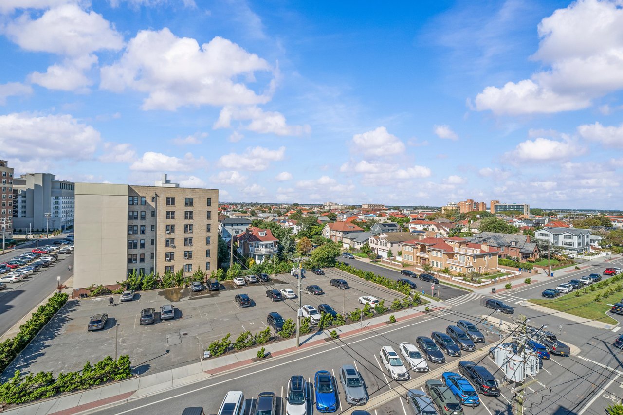 Aerial neighborhood view with apartment buildings, streets, parking lots, and blue sky.